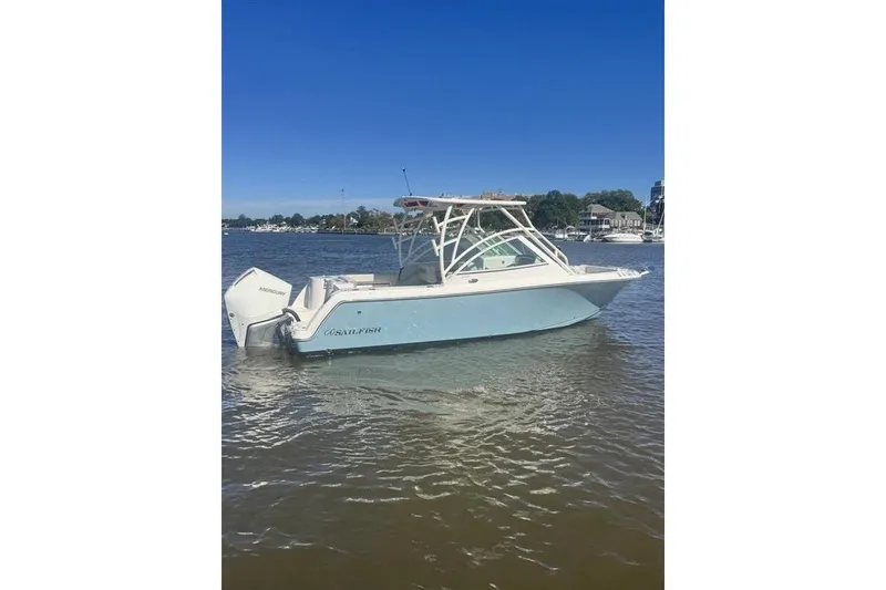 Slide: The Image of 2025 Sailfish 245 DC boat on calm water under clear blue sky. - 1
