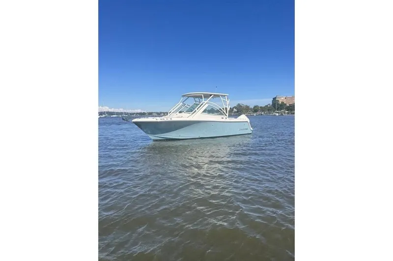 Slide: The Image of 2025 Sailfish 245 DC boat on calm water under clear blue sky. - 2