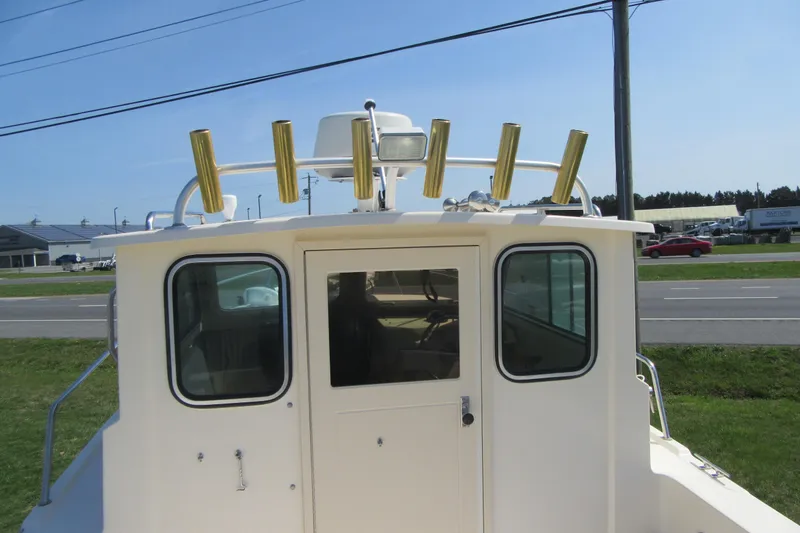 Slide: The Image of 2006 Parker 2120 Sport Cabin boat with rod holders, parked near a road. - 15