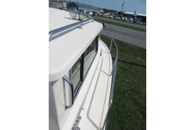 Slide: The Image of 2006 Parker 2120 Sport Cabin boat with railing and spotlight, parked near a road. - 17
