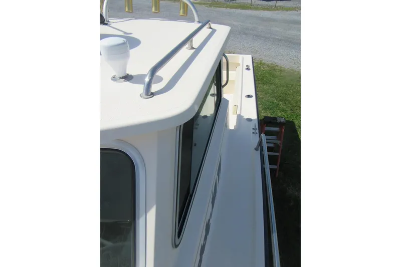 Slide: The Image of 2006 Parker 2120 Sport Cabin boat deck view with railing and cabin window. - 22