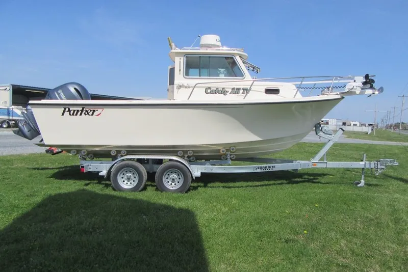 Slide: The Image of 2006 Parker 2120 Sport Cabin boat on trailer, parked on grass under clear blue sky. - 5