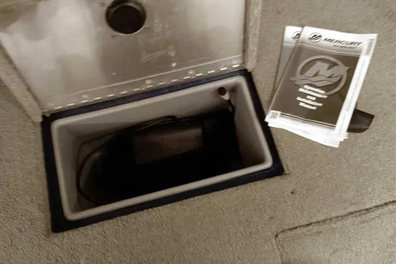 Slide: The Image of Open storage compartment in 2013 Tracker Pro Guide V-16 WT boat with manuals nearby. - 19