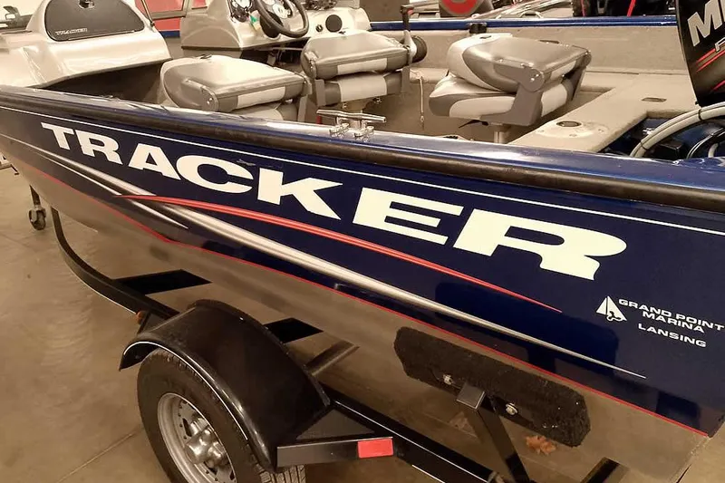 Slide: The Image of 2013 Tracker Pro Guide V-16 WT boat with seating and trailer in a showroom. - 4