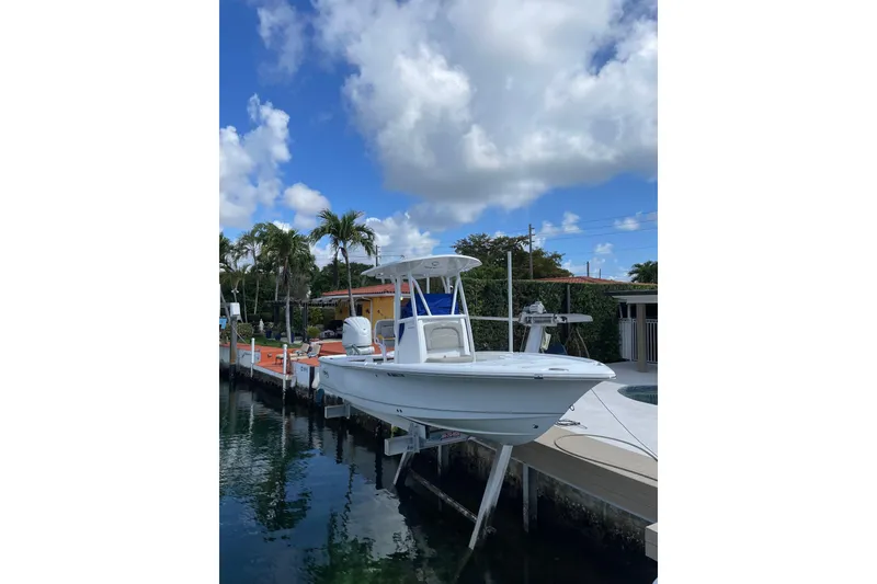 The Image of 2024 Sea Hunt BX 22 BR boat docked by a waterfront home under a blue sky. - 0
