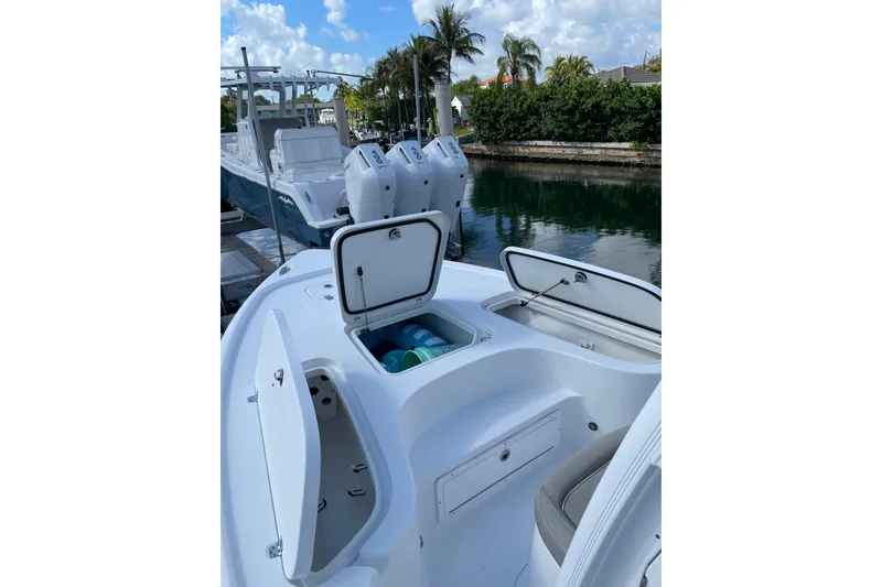 Slide: The Image of 2024 Sea Hunt BX 22 BR boat with open storage compartments, docked by a canal. - 13