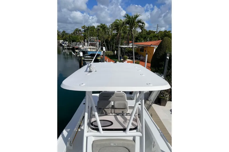 Slide: The Image of 2024 Sea Hunt BX 22 BR boat docked by a scenic waterfront with palm trees. - 14