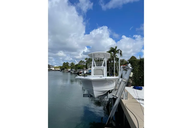Slide: The Image of 2024 Sea Hunt BX 22 BR boat docked on a calm waterway under a partly cloudy sky. - 15
