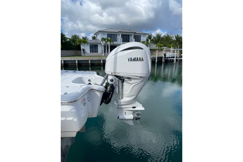 Slide: The Image of 2024 Sea Hunt BX 22 BR boat with Yamaha outboard motor, docked near waterfront home. - 2