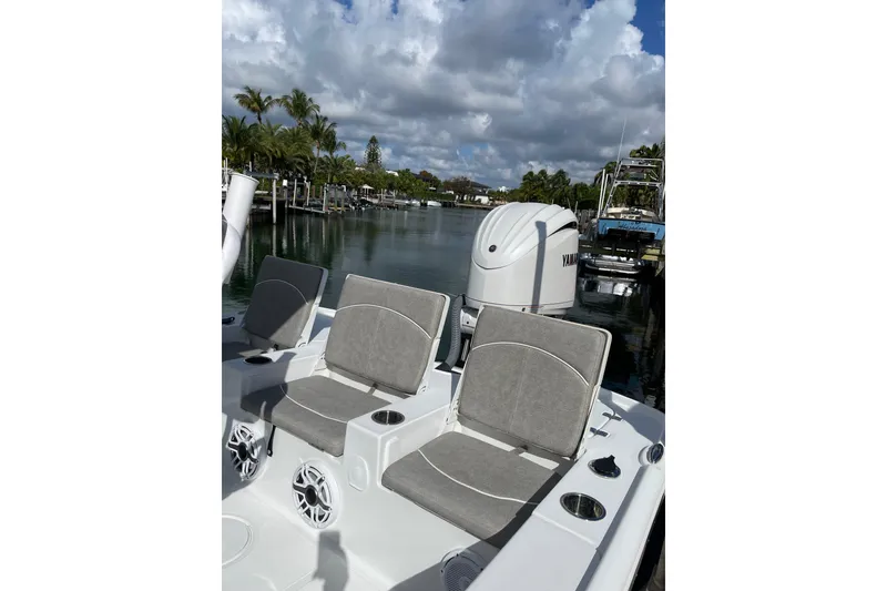 Slide: The Image of 2024 Sea Hunt BX 22 BR boat with seating and Yamaha engine, docked by palm trees. - 4
