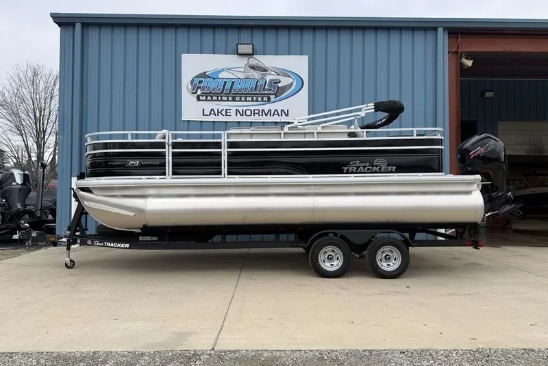 The Image of 2026 Sun Tracker Fishin' Barge 20 DLX pontoon boat on trailer at marine center. - 1