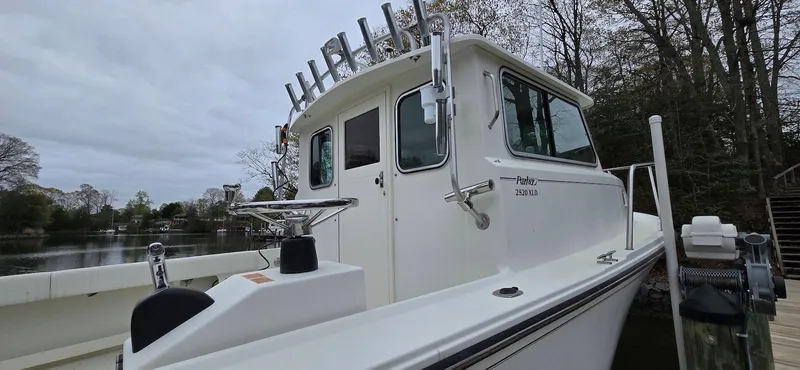 Slide: The Image of 2014 Parker 2520 XLD Sport Cabin boat docked by a wooded shoreline. - 3