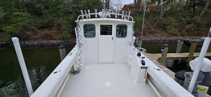 Slide: The Image of 2014 Parker 2520 XLD Sport Cabin boat docked, featuring spacious deck and cabin entrance. - 4