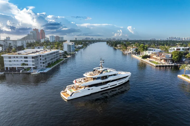 The Image of Luxurious 2024 Baglietto DOM 133 yacht cruising through a scenic urban waterway. - 0
