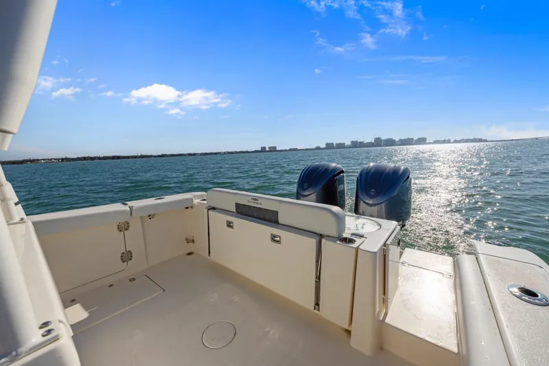 Slide: The Image of 2023 Cobia 301 Center Console boat on open water, featuring dual engines and a sunny sky. - 10