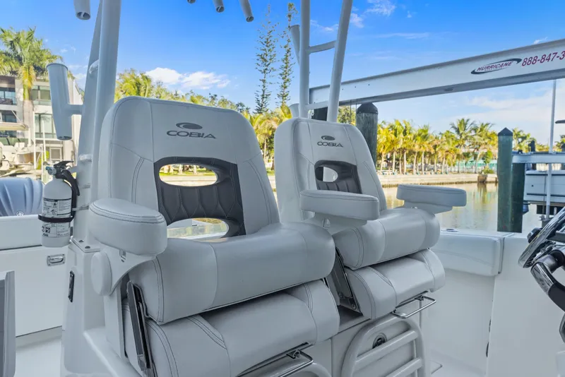 Slide: The Image of 2023 Cobia 301 Center Console boat seats with armrests, docked near palm trees. - 23