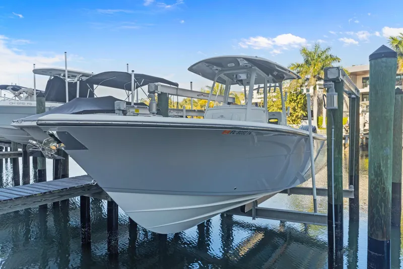 Slide: The Image of 2023 Cobia 301 Center Console boat docked on a lift, under a clear blue sky. - 27