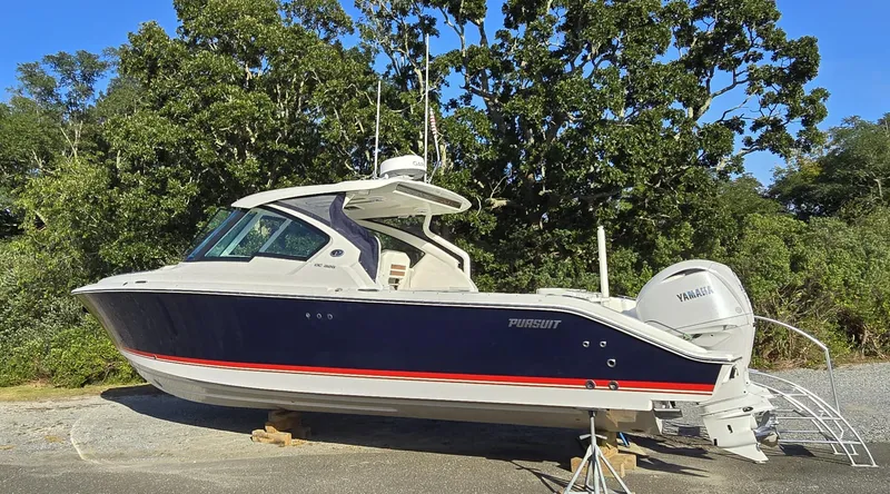 The Image of 2025 Pursuit DC 326 boat with Yamaha engines, parked outdoors, surrounded by trees. - 0