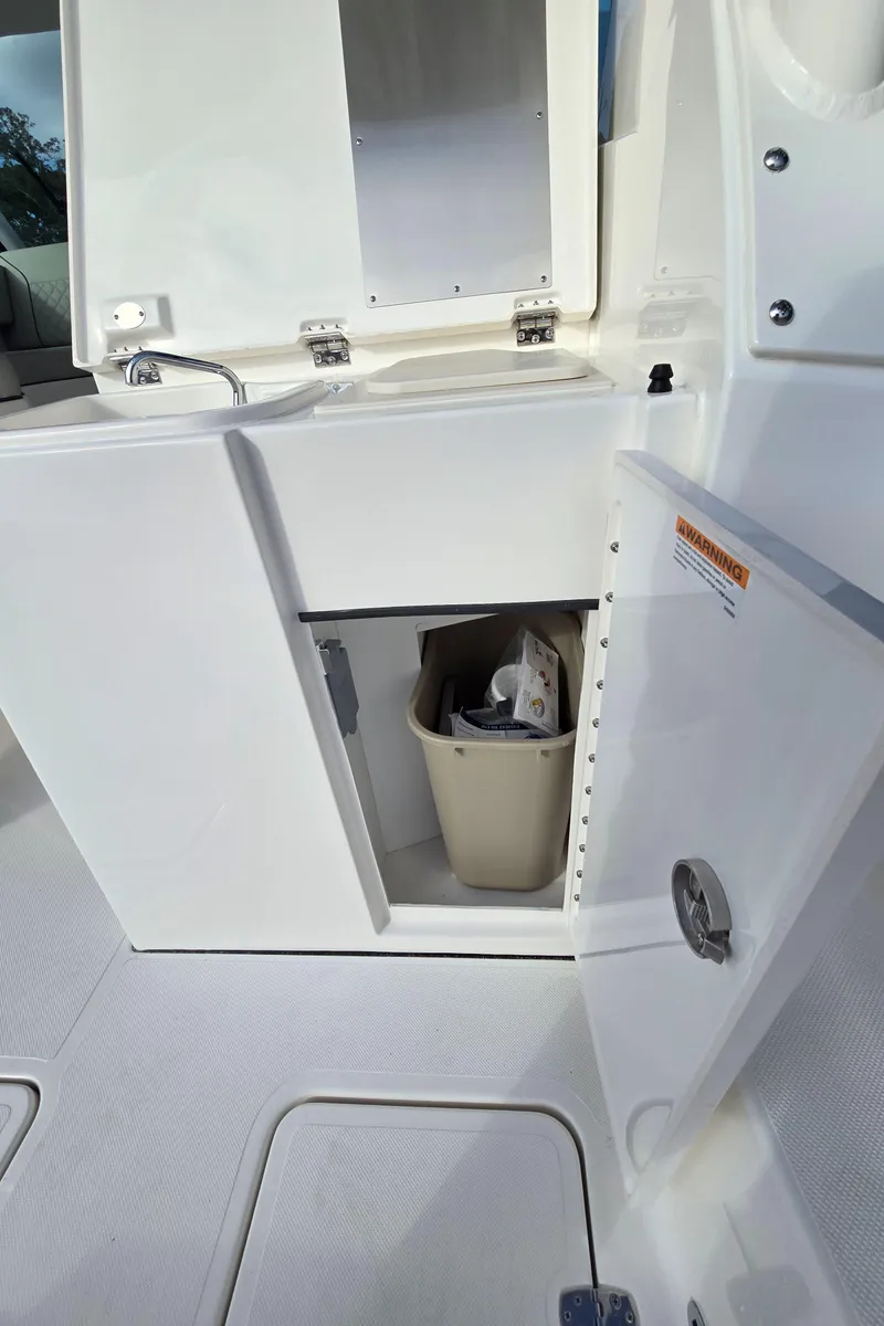 Slide: The Image of Open storage compartment on 2025 Pursuit DC 326 boat with trash bin inside. - 10