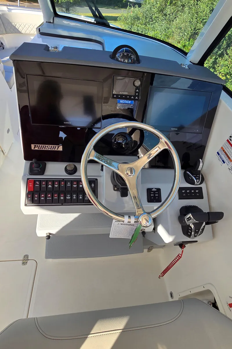 Slide: The Image of 2025 Pursuit DC 326 boat helm with steering wheel and control panel. - 14