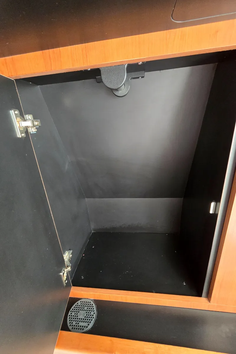 Slide: The Image of Open storage compartment in 2025 Pursuit DC 326 boat, featuring wooden trim and black interior. - 24