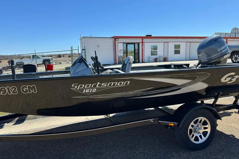 Slide: The Image of 2020 G3 Sportsman 1610 Camo boat with Yamaha motor on trailer, outdoor setting. - 20