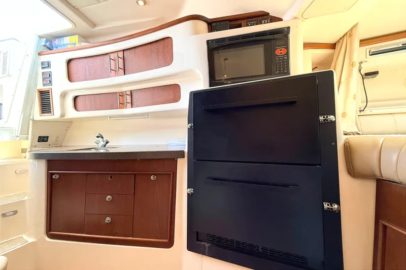 Slide: The Image of 2008 Grady-White Express 360 interior with kitchenette, featuring sink, microwave, and storage cabinets. - 11