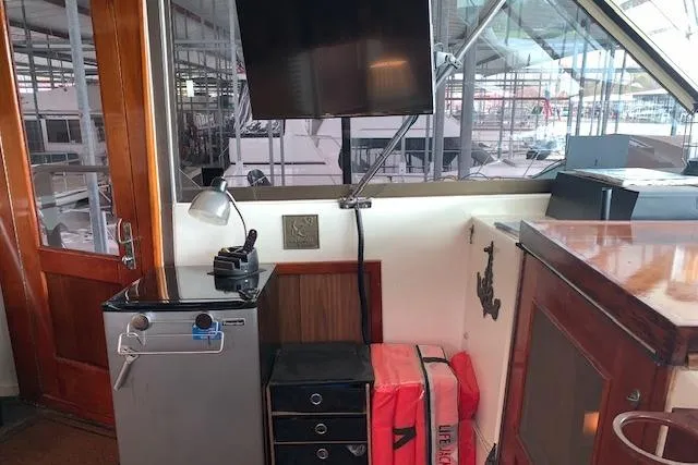 Slide: The Image of 1976 Hatteras 43 Double Cabin interior with TV, mini-fridge, and life jackets. - 12