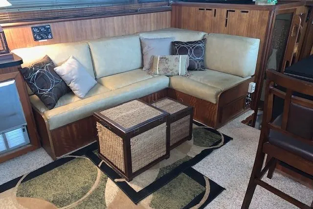Slide: The Image of 1976 Hatteras 43 Double Cabin interior with beige sofa, decorative pillows, and wicker coffee table. - 23