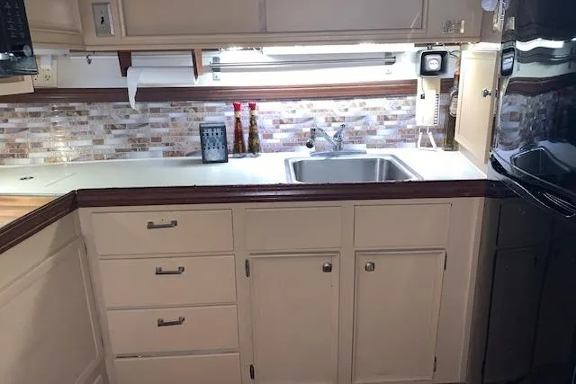 Slide: The Image of 1976 Hatteras 43 Double Cabin kitchen with modern backsplash, sink, and cabinetry. - 26