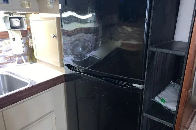 Slide: The Image of 1976 Hatteras 43 Double Cabin kitchen with black refrigerator and sink. - 29