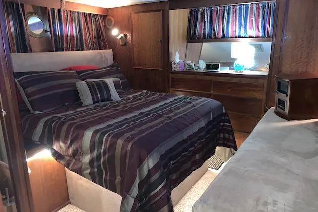 Slide: The Image of Cozy bedroom interior of 1976 Hatteras 43 Double Cabin with striped bedding and wooden furnishings. - 35