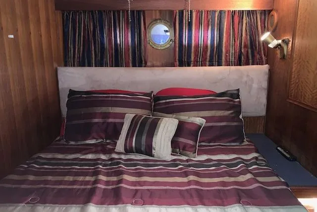 Slide: The Image of Cozy cabin interior of 1976 Hatteras 43 Double Cabin with striped bedding and porthole window. - 37