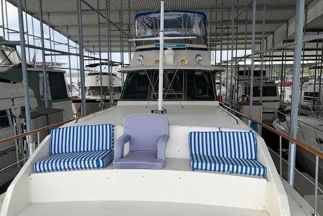 Slide: The Image of 1976 Hatteras 43 Double Cabin yacht with striped seating on deck, docked in marina. - 5