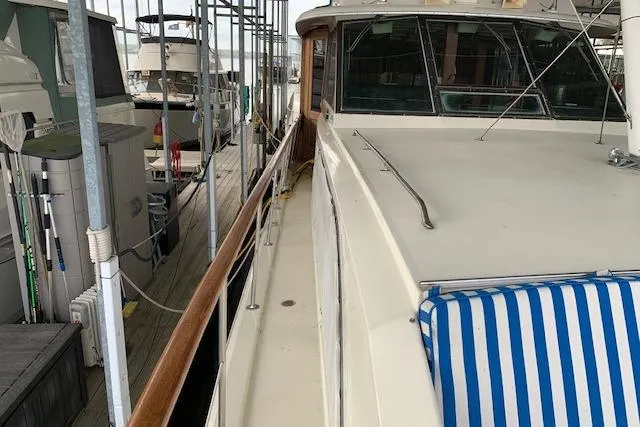 Slide: The Image of 1976 Hatteras 43 Double Cabin yacht docked, featuring a spacious deck and striped cushion. - 6