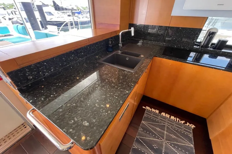 Slide: The Image of Luxurious yacht kitchen with black granite countertops, wooden cabinetry, and modern sink. Serenity 64, 2018. - 28