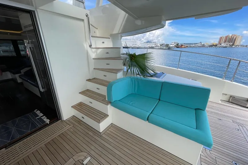 Slide: The Image of Luxurious Serenity 64 yacht deck with turquoise seating, wooden flooring, and marina view. - 7