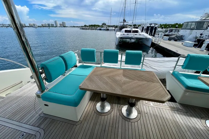 Slide: The Image of Luxurious Serenity 64 yacht deck with turquoise seating and wooden table, docked at marina. - 8
