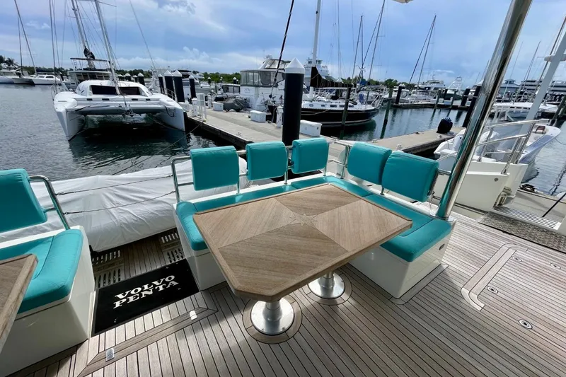 Slide: The Image of Luxurious Serenity 64 yacht deck with turquoise seating, wooden table, and marina view. - 9