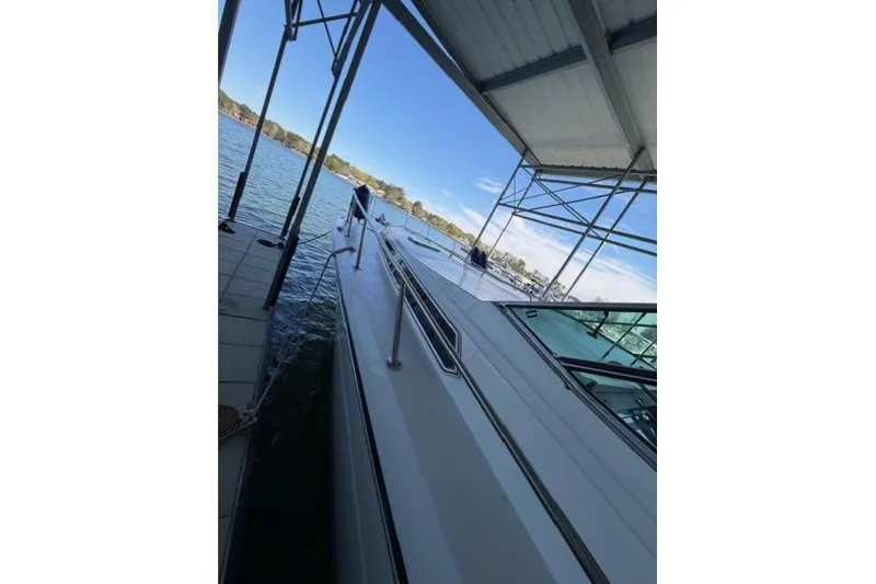 Slide: The Image of 1989 Sea Ray 460 Express Cruiser docked under a covered marina with scenic water view. - 10