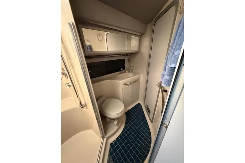 Slide: The Image of 1989 Sea Ray 460 Express Cruiser bathroom with blue-tiled floor and compact design. - 23