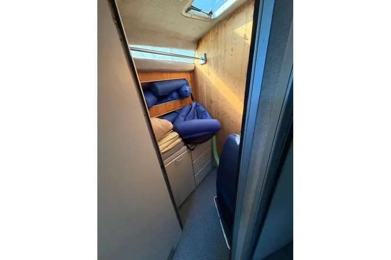 Slide: The Image of 1989 Sea Ray 460 Express Cruiser cabin interior with blue cushions and wooden paneling. - 25