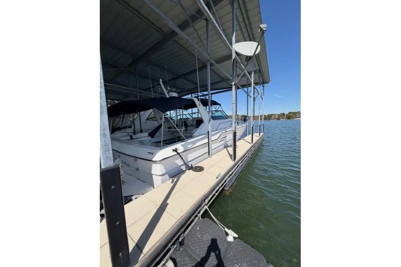 Slide: The Image of 1989 Sea Ray 460 Express Cruiser docked under a covered marina on a sunny day. - 4