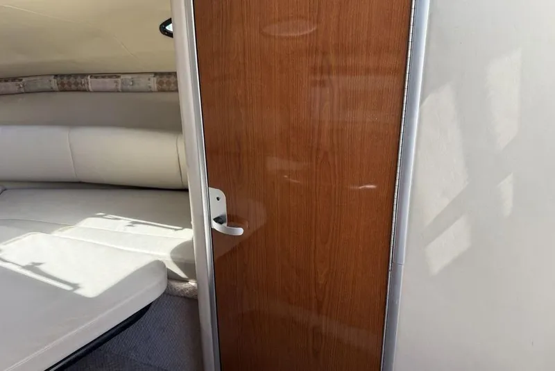 Slide: The Image of Interior cabin view of a 2000 Chaparral Signature 240 boat, featuring a wooden door and cushioned seating. - 31