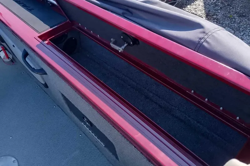 Slide: The Image of 2018 Tracker Targa V-18 Combo boat storage compartment, open with red trim and gray interior. - 40