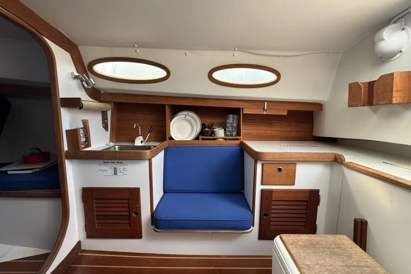 Slide: The Image of Interior of a 2017 Alerion Express 28 sailboat with wooden cabinetry and blue seating. - 18
