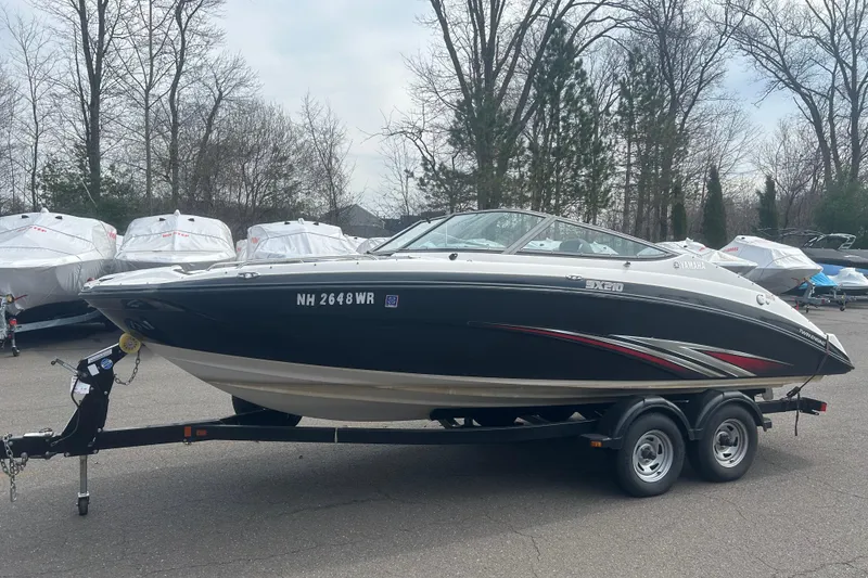 The Image of 2015 Yamaha Boats SX210 on trailer, parked outdoors with other boats. - 0