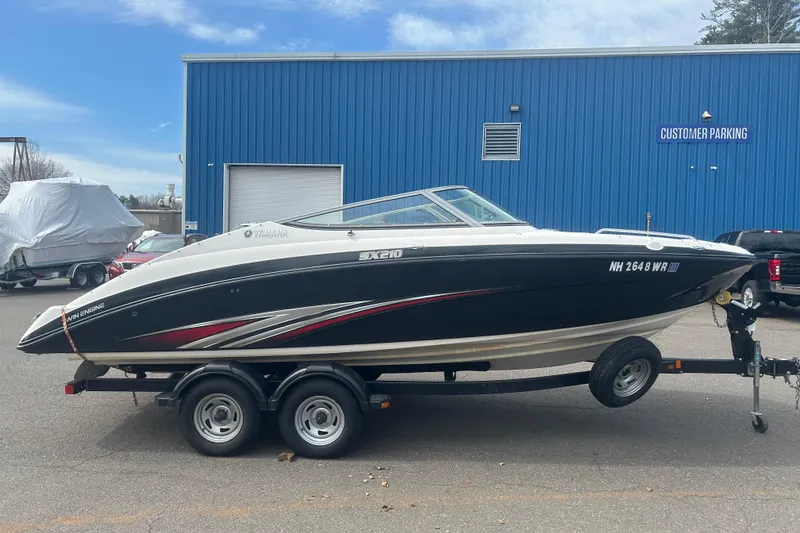 Slide: The Image of 2015 Yamaha Boats SX210 on trailer, parked near blue building. - 4
