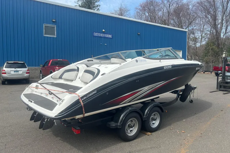 Slide: The Image of 2015 Yamaha Boats SX210 on trailer, parked outside a blue building. - 5