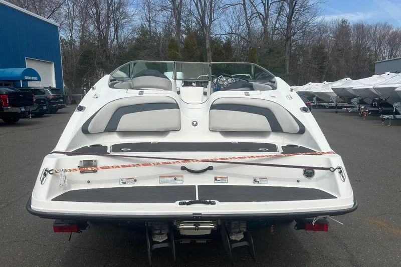 Slide: The Image of 2015 Yamaha Boats SX210, rear view in a boatyard with trees and trailers. - 6